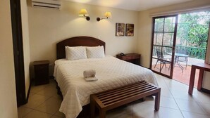 Un dormitorio con cama, mesitas de noche, aire acondicionado, lámparas fijadas a la pared y vistas al exterior a través de un ventanal corredera.