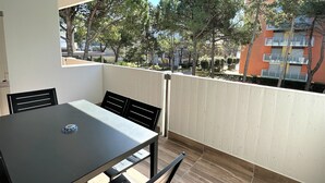 Un balcón con una mesa y sillas, con vistas a un barrio residencial con árboles y edificios.