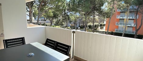 A balcony with a table and chairs, overlooking a residential area with trees and buildings.