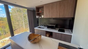 Una cocina moderna con un ventanal grande, un cuenco de madera y un microondas.