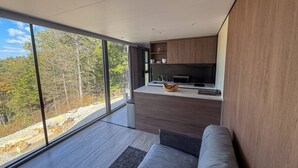 Un interior moderno con un ventanal grande, una zona de cocina y un espacio de estar.