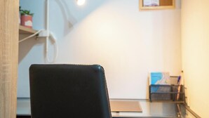 Een kamer met een zwarte stoel, een bureau, een lamp en een plank met een plant.