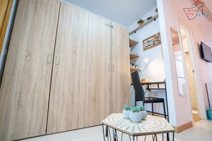 Una habitación con un armario de madera, una mesa de comedor con sillas y una mesita con plantas en macetas.