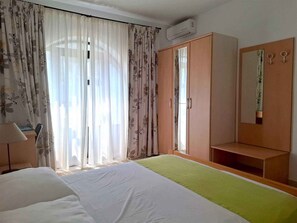 Hotellihuone, jossa on sänky, vaatekaappi, peili ja lamppu.
