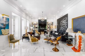 A spacious living room with a fireplace, bookshelves, and a chandelier.