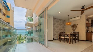 Un appartamento moderno con un balcone affacciato su una vista cittadina, un'area pranzo con tavolo e sedie, e una ventola a soffitto.