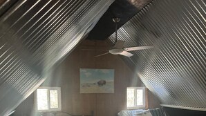 Un dormitorio acogedor en el desván con dos camas, un ventilador de techo y un cuadro de un bisonte.