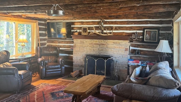 Acogedor interior de cabaña de madera con sillones de cuero, una mesa de centro de madera y una chimenea.