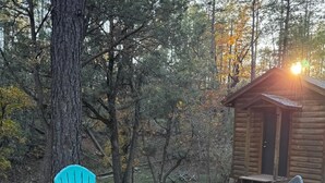 Una cabaña de madera con un patio que tiene asientos al aire libre y un brasero.