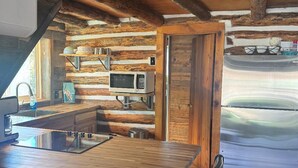 Una cocina rústica con una isla de madera, taburetes de bar, un microondas y un refrigerador.