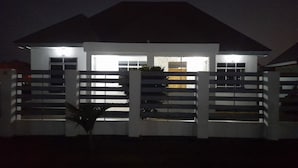A modern house with a white exterior, a gated entrance, and a visible door.