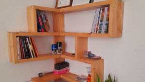Ein Holzbücherregal mit verschiedenen Gegenständen, darunter Bücher, eine Pflanze und Zeugnisse.