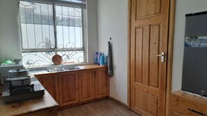 Eine Küche mit Holzausstattung, einem Gasherd, einem Spülbecken und einem Fenster mit Metallgitter.