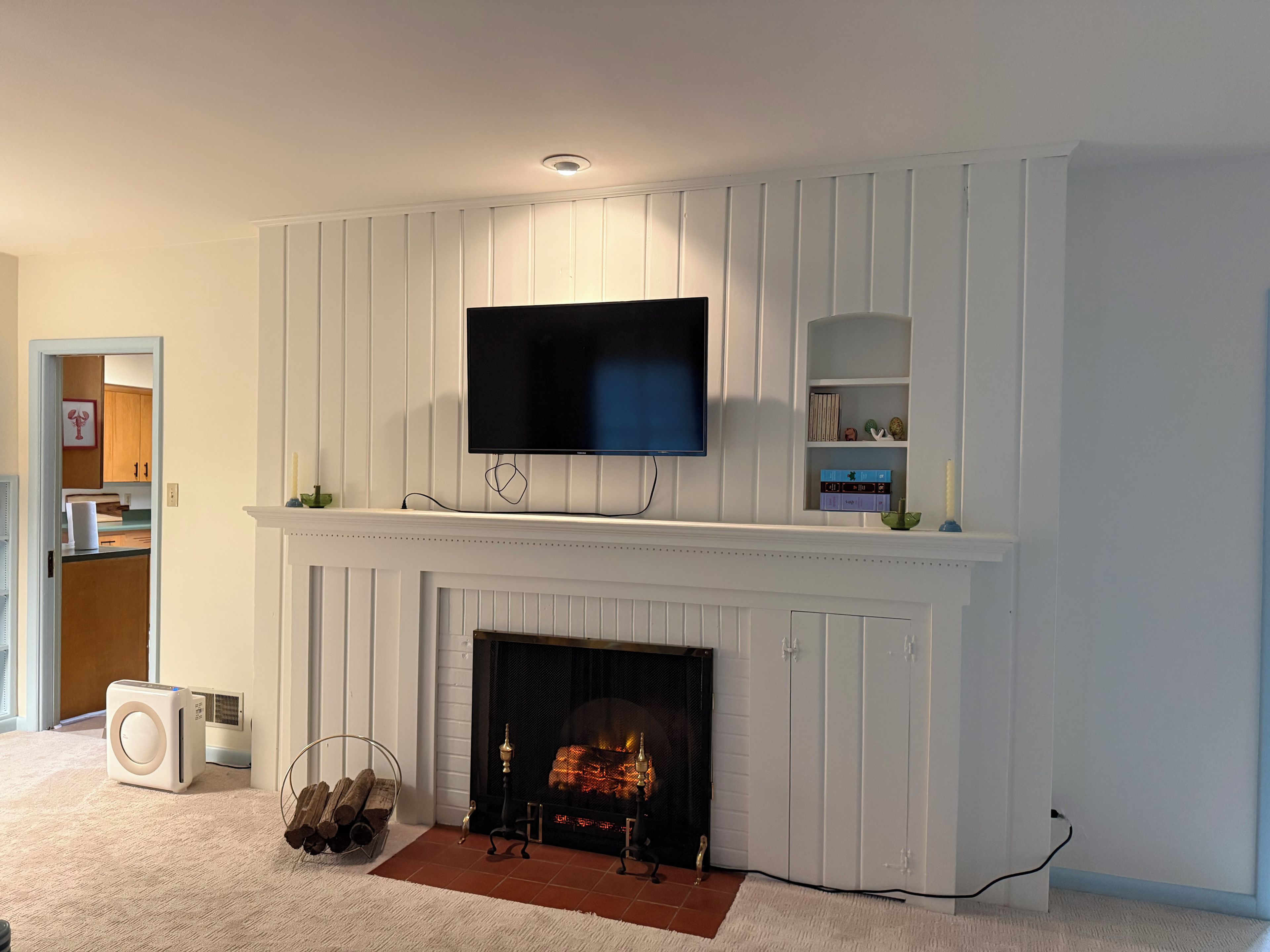 A living room with a fireplace, a mounted television, and a bookshelf.