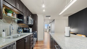A modern kitchen with dark wood cabinets, stainless steel appliances, and a granite countertop.