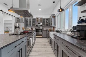 A modern kitchen with stainless steel appliances, grey cabinetry, and pendant lighting. - Luxury 4BR | Pool, Gym, Fireplace & Outdoor Dining (Sarasota)