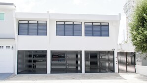 Ein modernes, zweistöckiges Gebäude mit Garageneinfahrt, das eine helle, weiße Fassade und schwarze Metalldarren aufweist.
