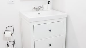 Ein weißes Badezimmer-Waschbecken mit Spiegel, Waschbecken und Toilettenpapierhalter.
