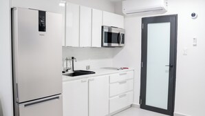 Eine moderne Küche mit weißen Schränken, einer eingebauten Mikrowelle und einem Kühlschrank.