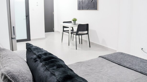 Ein modernes Schlafzimmer mit Bett, Nachttisch und kleinem Schreibtisch mit Stuhl.