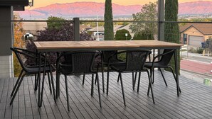 A balcony with a wooden table and four chairs, overlooking a cityscape with mountains in the background. - Palisades hills home with City Mountain View’s  (Albuquerque)