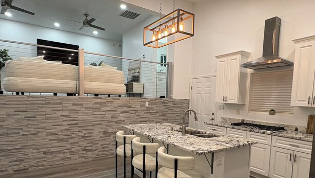 A modern kitchen with a marble countertop, bar stools, and a built-in island. - Palisades hills home with City Mountain View’s  (Albuquerque)
