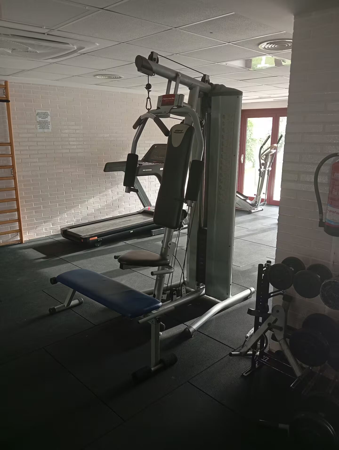 A gym with a treadmill, weight bench, and various exercise machines.