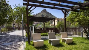 A covered outdoor seating area with chairs and a table, surrounded by a grassy lawn and a paved walkway. - Luxury penthouse with swimming pool, jacuzzi and gym near the spa of archena (MC)
