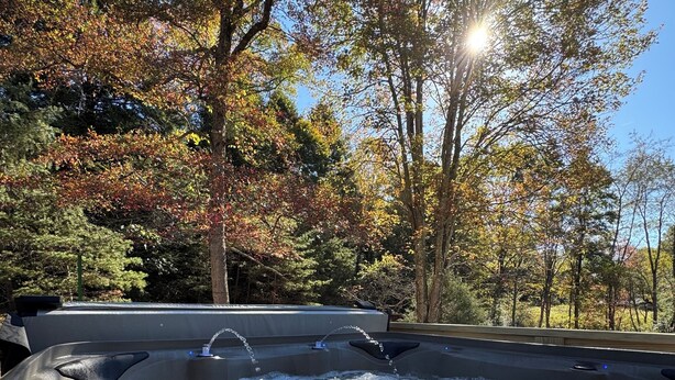 A hot tub with water flowing, surrounded by trees with autumn foliage.