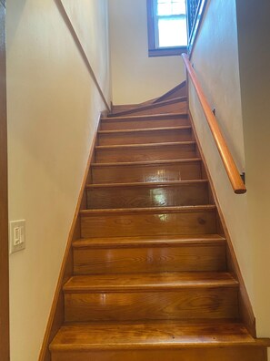 Un escalier en bois, doté d’une rampe, menant à un palier.