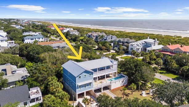 A coastal residential area with a prominent blue house featuring a balcony and a swimming pool.