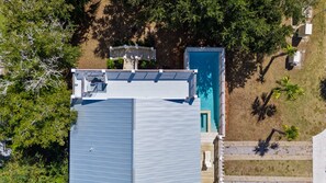 Un edificio residencial con terraza en la azotea, piscina y un pequeño jardín.