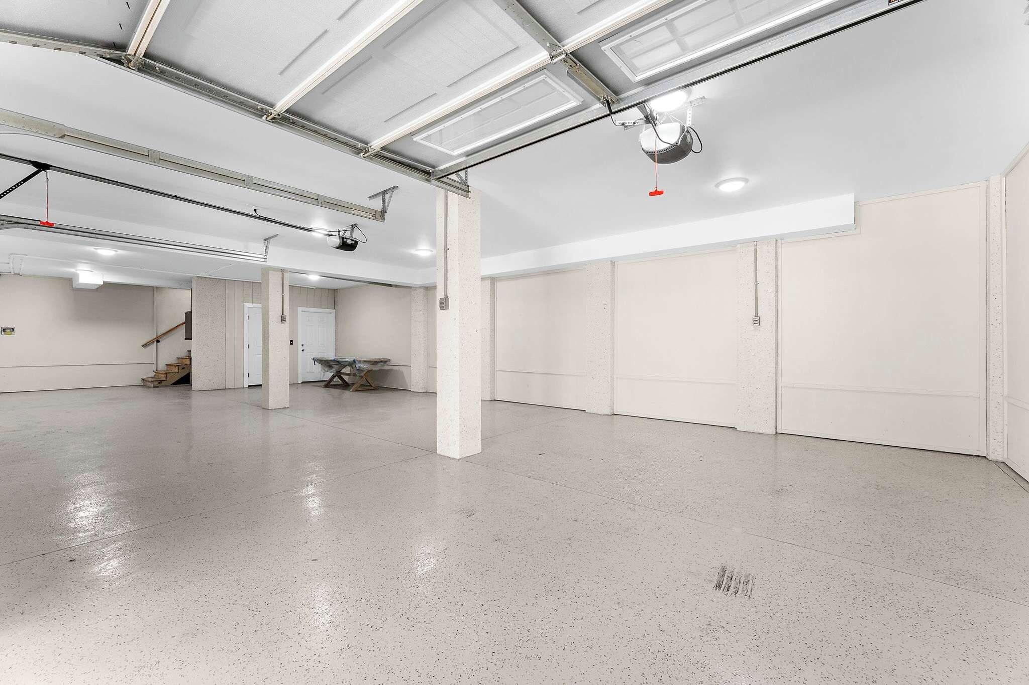 Un vaste espace intérieur doté d’un sol en béton poli, de murs blancs et d’un plafond haut avec des conduits apparents.