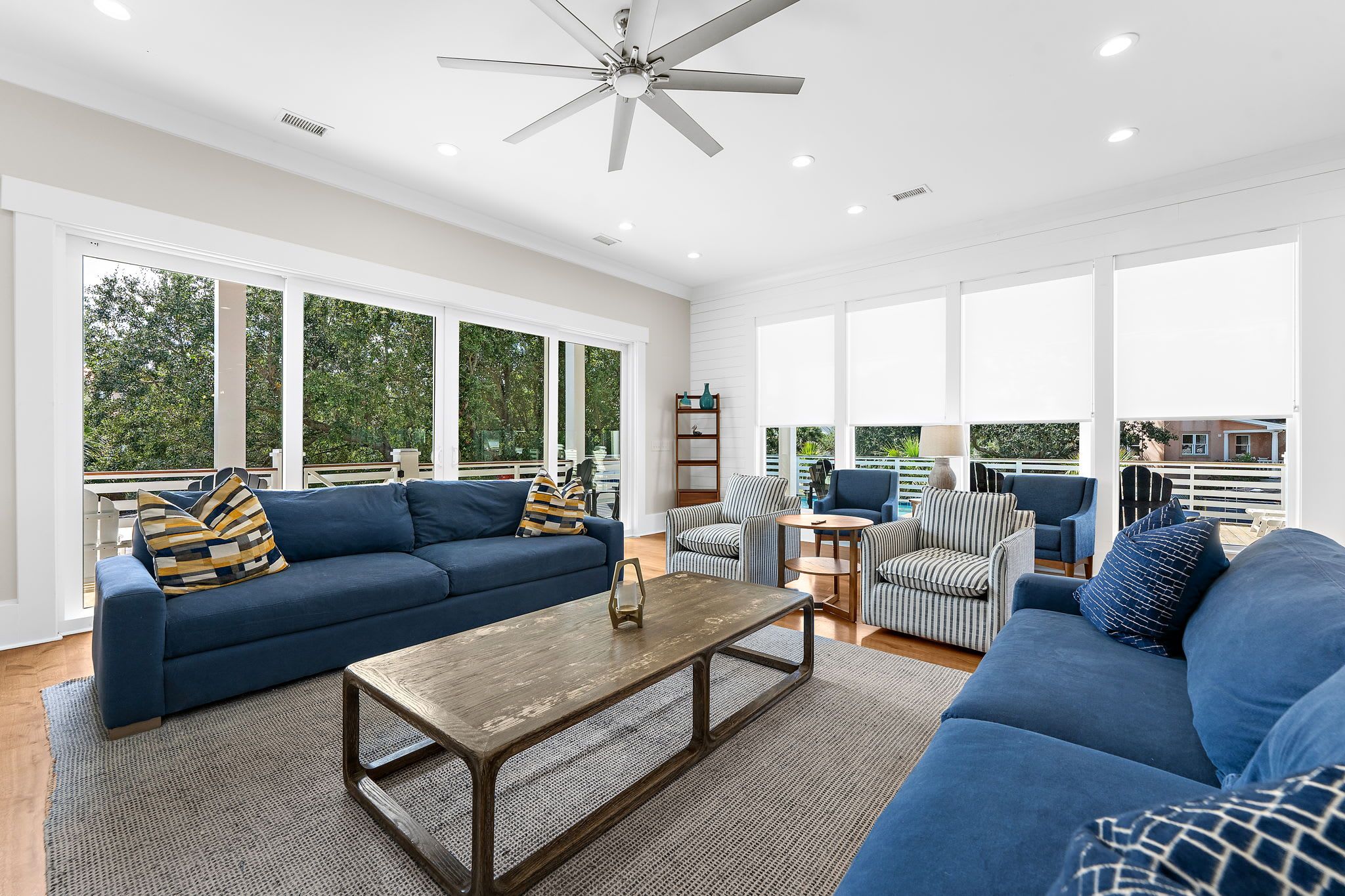 A spacious living area with a large sofa, a coffee table, and a striped armchair.
