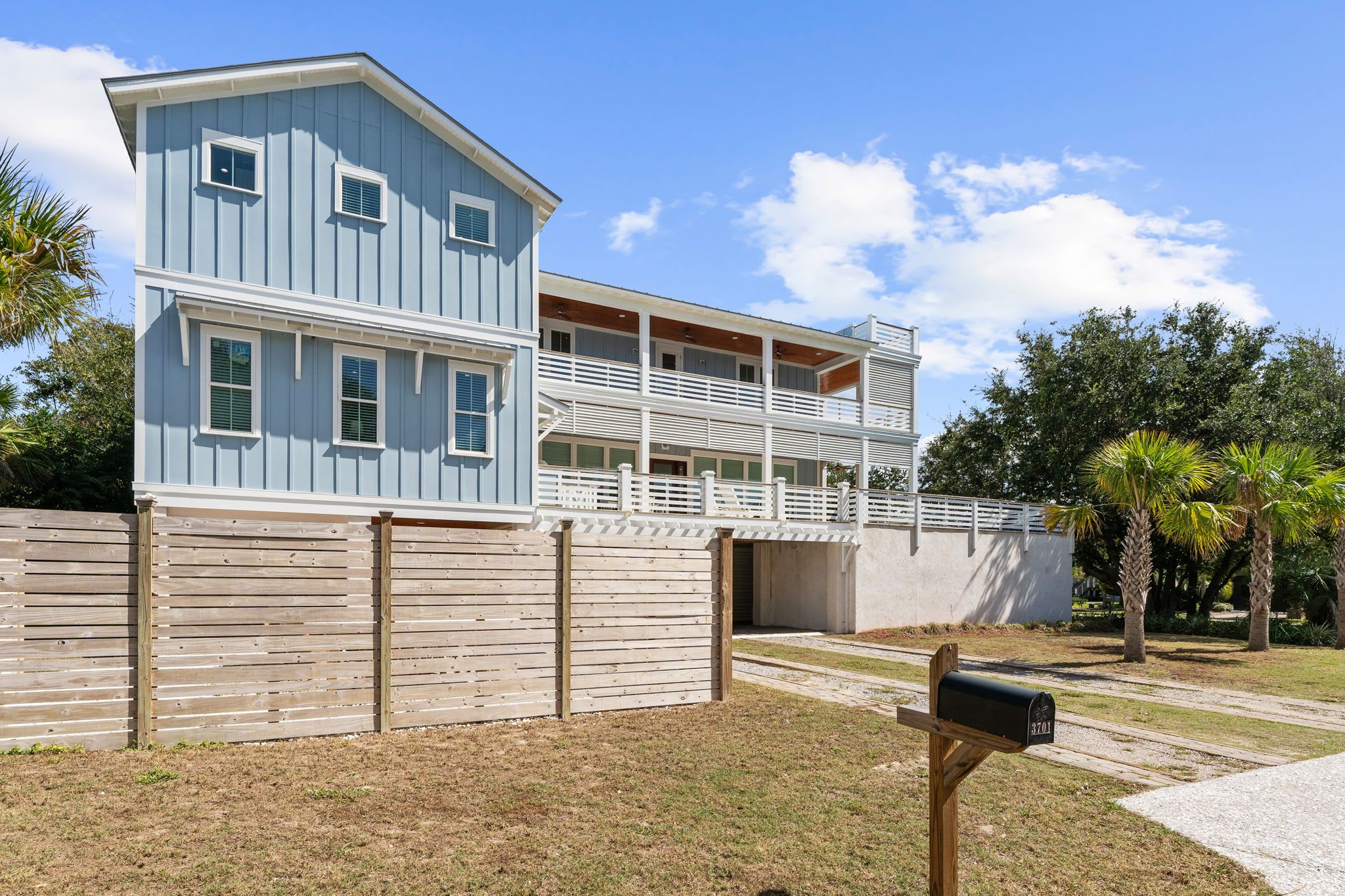A two-story building with a balcony, a wooden fence, and a mailbox.