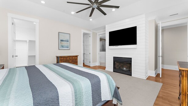 Une chambre à coucher comprenant un lit, un téléviseur, une cheminée et un ventilateur de plafond.