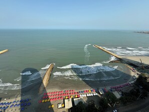 A beach with a long stretch of umbrellas and beach chairs, a sandy shore, and waves crashing onto the beach. - Apartamentos Palmetto Eliptic ICDI (Cartagena)