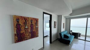 A modern living room with a large window, a teal sofa, and abstract art on the wall. - Apartamentos Palmetto Eliptic ICDI (Cartagena)
