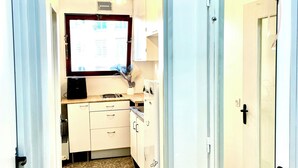 A narrow hallway leading to a kitchen with white cabinets, a tiled floor, and a small window. - Paris appartment Eiffel Tour (Paris)