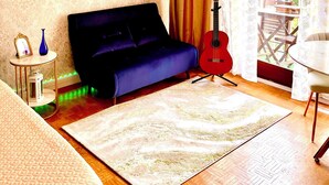 A room with a blue sofa, a red guitar, a round mirror, and a patterned rug. - Paris appartment Eiffel Tour (Paris)