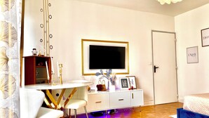 A modern bedroom with a bed, a TV, a desk with chairs, and a bedside table with decorative items. - Paris appartment Eiffel Tour (Paris)