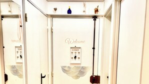 A hallway with a wooden floor, white walls, and a door with a 'Welcome' sign and a 'Home' sign. - Paris appartment Eiffel Tour (Paris)