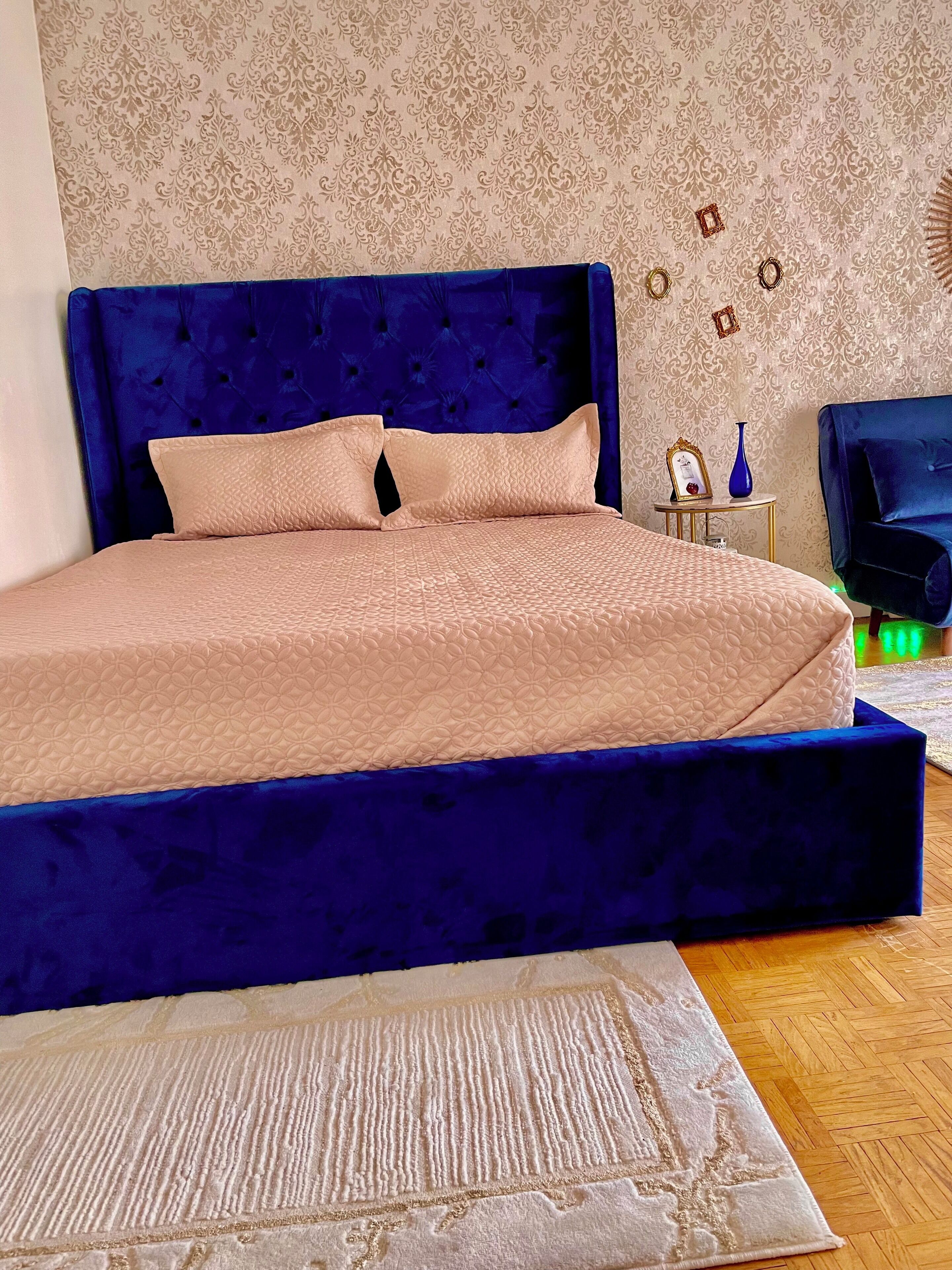 Una camera da letto con un letto grande, una testiera blu e una parete decorata.