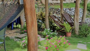 Un jardin agrémenté d’un hamac, de chaises longues et d’une variété de plantes et de fleurs.
