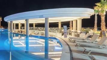 A pool area with lounge chairs and a covered seating area.