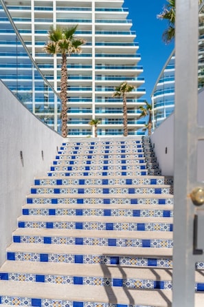 Eine Treppe mit blau-weißen gemusterten Fliesen führt zu einem modernen Gebäude mit Balkonen.