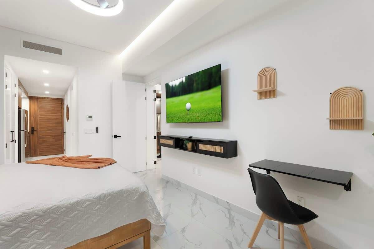 Ein modernes Schlafzimmer mit einem Bett, einem Schreibtisch und einem Fernseher an der Wand.