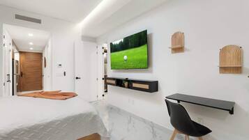 Ein modernes Schlafzimmer mit einem Bett, einem Schreibtisch und einem Fernseher an der Wand.