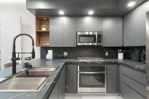 Una cocina moderna con microondas integrado, horno y pileta de acero inoxidable.