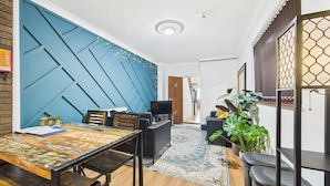 Una sala de estar moderna con una pared azul de acento, una mesa de comedor de madera y una planta grande.